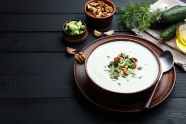 Siyah ahşap masada servis edilen dereotlu ve cevizli lezzetli salatalık çorbası. Metin için boşluk
