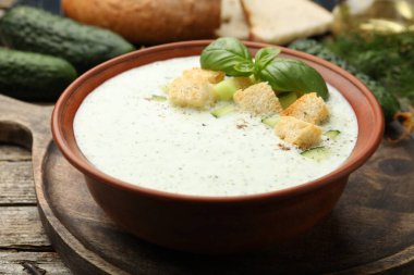 Salatalık çorbası, kızarmış ekmek, fesleğen, ekmek ve sebzeler ahşap masada, yakın plan.