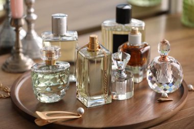 Farklı parfüm şişeleri ve aksesuarlar ahşap masada, yakın plan.