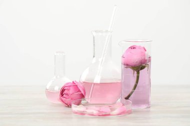 Lüks parfüm yapıyorum. Temel yağlar cam süslemede ve çiçekler beyaz ahşap masada, yakın plan.