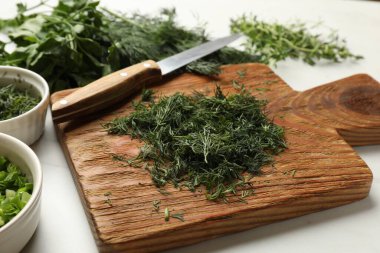 Farklı taze otlar ve beyaz mermer masada bıçak, yakın plan.