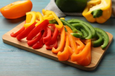 Mavi ahşap masada renkli dolmalık biberler kes, yakın plan.