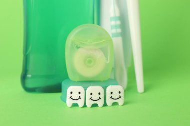 Yeşil arka planda farklı oral bakım ürünleri ve diş figürleri, yakın plan