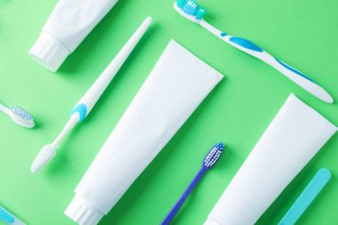 Yeşil zemin üzerinde diş fırçası ve tüpler düz yatıyordu.