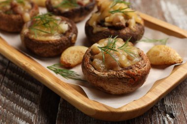 Eritilmiş peynirli, sarımsaklı ve dereotlu lezzetli mantarlar ahşap masa, yakın plan.