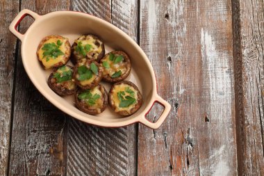 Eritilmiş peynirli ve maydanozlu leziz mantarlar ahşap masa üzerinde, üst manzara. Metin için boşluk