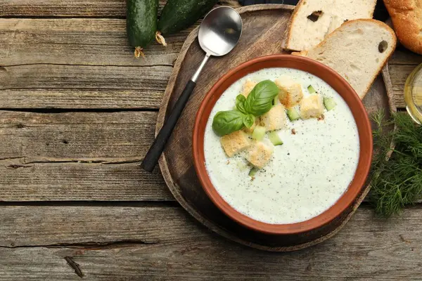 Ahşap masada servis edilen kıtır kıtır salatalık çorbası ve fesleğen. Metin için boşluk