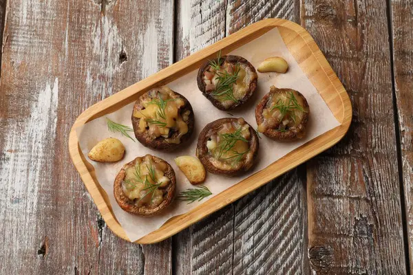 Eritilmiş peynirli, sarımsaklı ve dereotlu lezzetli mantarlar ahşap masa, üst manzara.