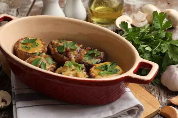 Eritilmiş peynirli ve maydanozlu lezzetli mantarlar ahşap masa üzerinde, yakın plan.