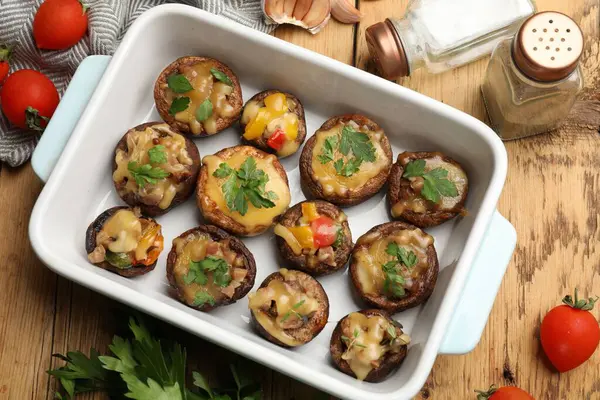 Ahşap masaya konmuş, ahşap tabakta ve malzemelerde lezzetli mantarlar var.