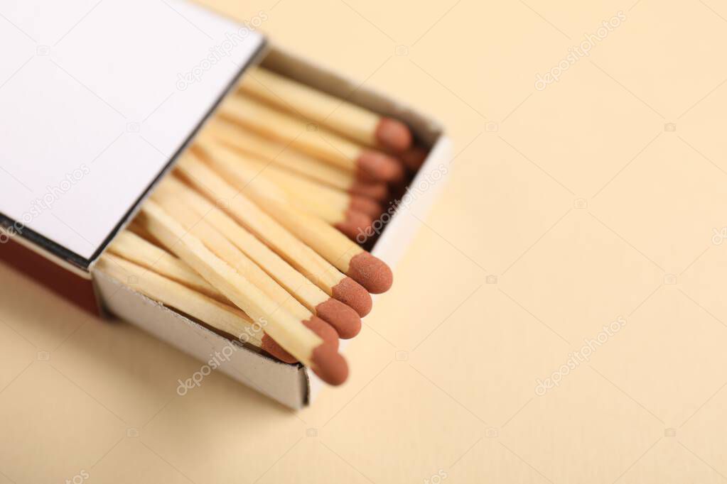 Matches in box on beige background, closeup. Space for text