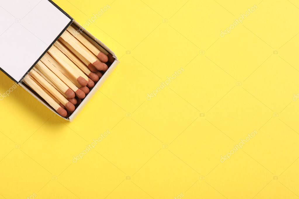 Matches in box on yellow background, top view. Space for text