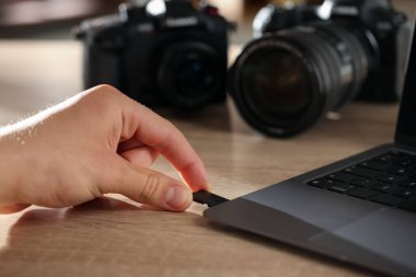 SD bellek kartını bilgisayarın içine yerleştiren adam ahşap masa, yakın plan