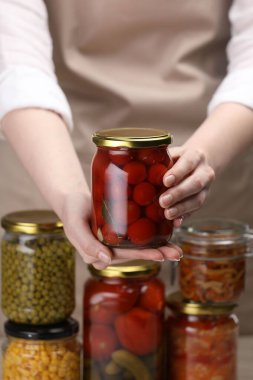 Farklı turşulu ürünlerle dolu kavanozları olan kadın, yakın plan.