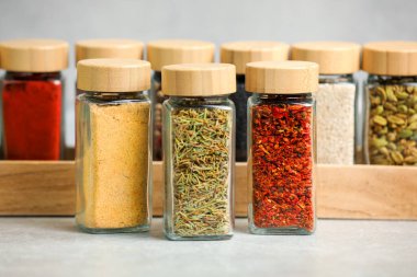 Açık gri masadaki kavanozlardaki farklı aromatik baharatlar.