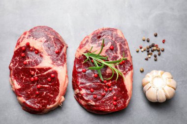 Çiğ et parçaları ve baharatlar gri dokulu masa üzerinde, düz yatıyordu.