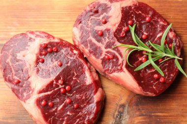 Ahşap masada çiğ et ve baharat parçaları.