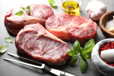 Çiğ et, baharat ve çatal parçaları gri masada, yakın plan.