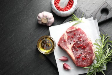 Bir parça çiğ et ve baharat siyah masada, düz yerde. Metin için boşluk