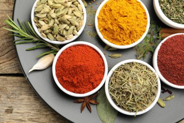 Ahşap masada farklı aromatik baharatlar, üst görünüm.