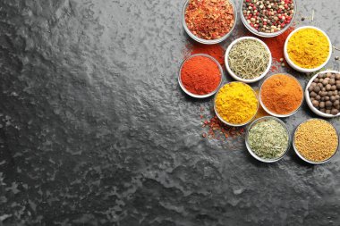 Tabaklardaki farklı aromatik baharatlar karanlık masada, düz yerde. Metin için boşluk