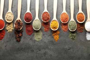 Gri masadaki kaşıklarda bir sürü farklı baharat var. Metin için boşluk
