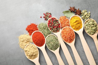 Gri masadaki kaşıklardaki farklı baharatlar düzdü.