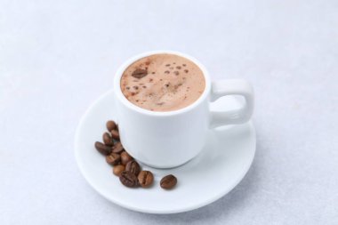 Aromatik kahve fincanda, fasulye ve çay tabağı ışık masasında, yakın plan.