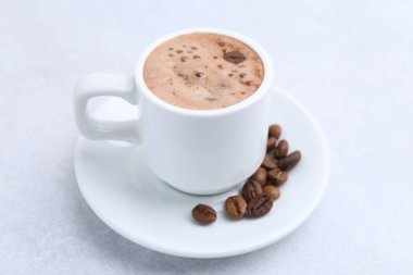 Aromatik kahve fincanda, fasulye ve çay tabağı ışık masasında, yakın plan.