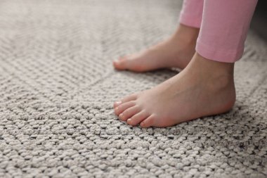 Evdeki gri halıdaki kız, yakın plan.