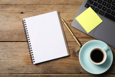 Kalemli defter, yapışkan not, dizüstü bilgisayar ve kahve ahşap masada, düz yatıyordu.