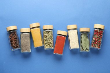 Mavi arka planda kavanozlarda farklı aromatik baharatlar var.