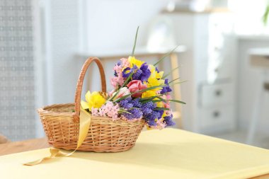 İçerideki masada güzel çiçekler olan hasır sepet.