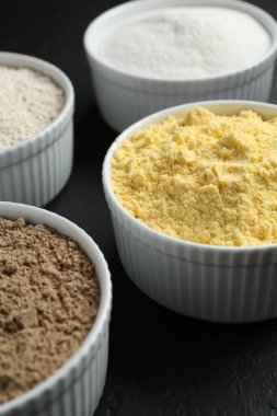 Siyah masadaki kaselerdeki farklı un türleri, yakın plan.