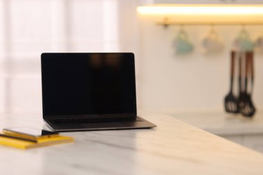 Mutfaktaki beyaz mermer masada boş ekranlı dizüstü bilgisayar, seçici odaklanma. Tasarım için model