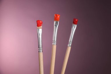 Pembe arka planda renkli üç fırça, yakın plan.