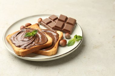 Lezzetli çikolatalı tostlar, parçalar, nane ve fındıklar ışık masasında, yakın plan