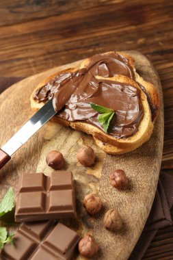 Lezzetli çikolatalı tostlar, parçalar, nane ve fındıklar ahşap masada, yakın plan.