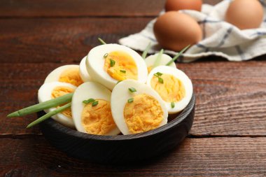 Haşlanmış yumurta ve ahşap masada yeşil soğan, yakın plan.