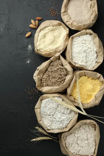 Siyah masa üzerinde, kağıt torbalarda farklı tipte un, düz yerde.