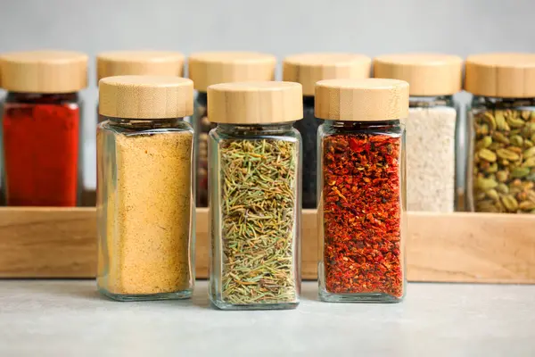 Açık gri masadaki kavanozlardaki farklı aromatik baharatlar.