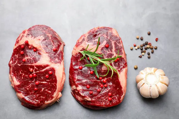 Çiğ et parçaları ve baharatlar gri dokulu masa üzerinde, düz yatıyordu.