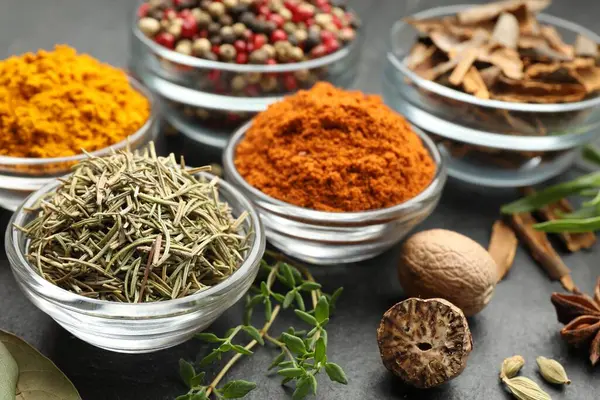 Gri masada farklı aromatik baharatlar, yakın plan.