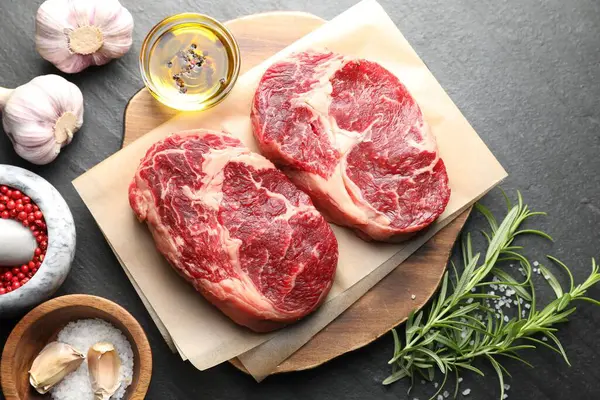 Çiğ et parçaları ve baharatlar siyah masanın üzerinde, düz yatıyordu.