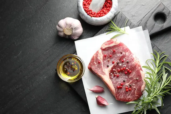 Bir parça çiğ et ve baharat siyah masada, düz yerde. Metin için boşluk