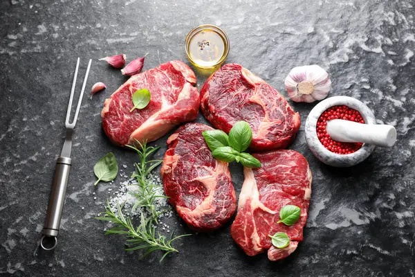 Çiğ et, baharat ve çatal. Koyu masada, düz yerde.
