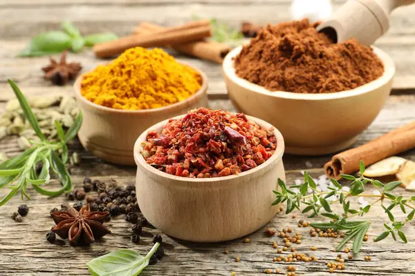 Ahşap masada farklı aromatik baharatlar, yakın plan.