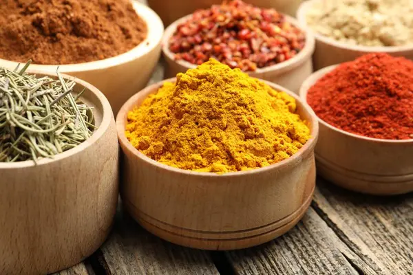 Tahta masadaki kaselerde farklı aromatik baharatlar, yakın plan.