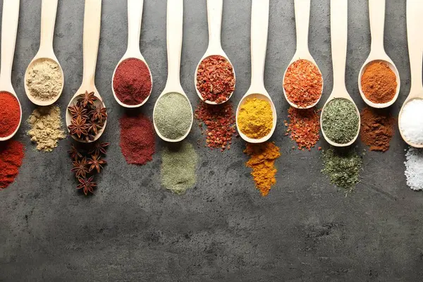 Gri masadaki kaşıklarda bir sürü farklı baharat var. Metin için boşluk