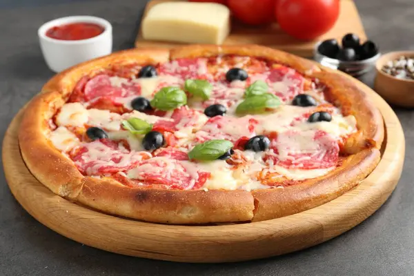 Gri masada lezzetli pizza ve malzemeler, yakın plan.